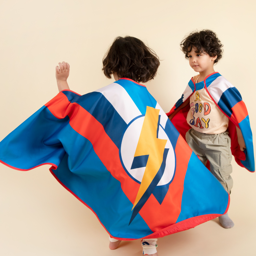 Enfant Souriant Portant Une Cape De Super-héros Et Un Masque Se Cognant Les  Poings Sur Fond Bleu En Studio Et Regardant La Caméra